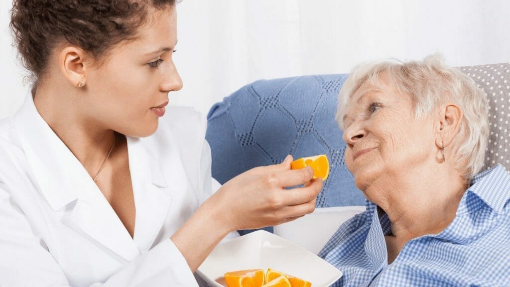 Caregiver feeds elder woman to protect her from choking hazards