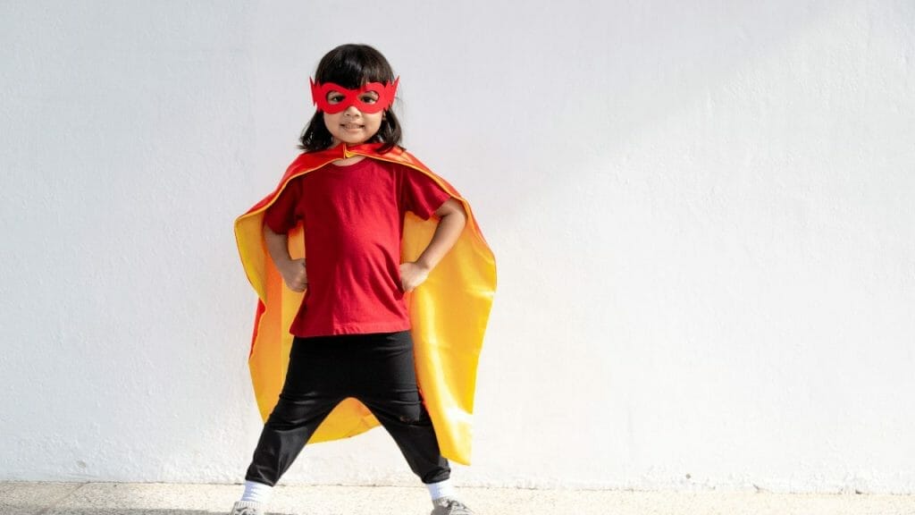 Girl dressed as a superhero with a cape and a mask