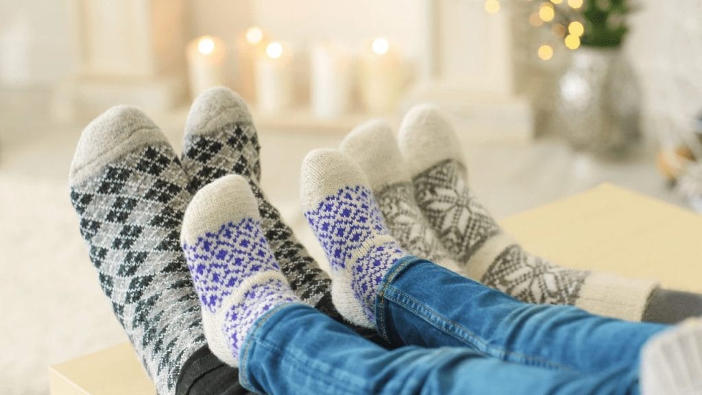 Father, mother and kid's feet with winter socks in a cozy room during family vacation