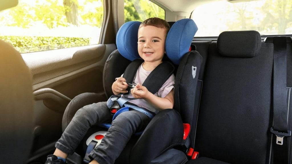 A young boy sitting in a children car seat to ensure child safety in the car