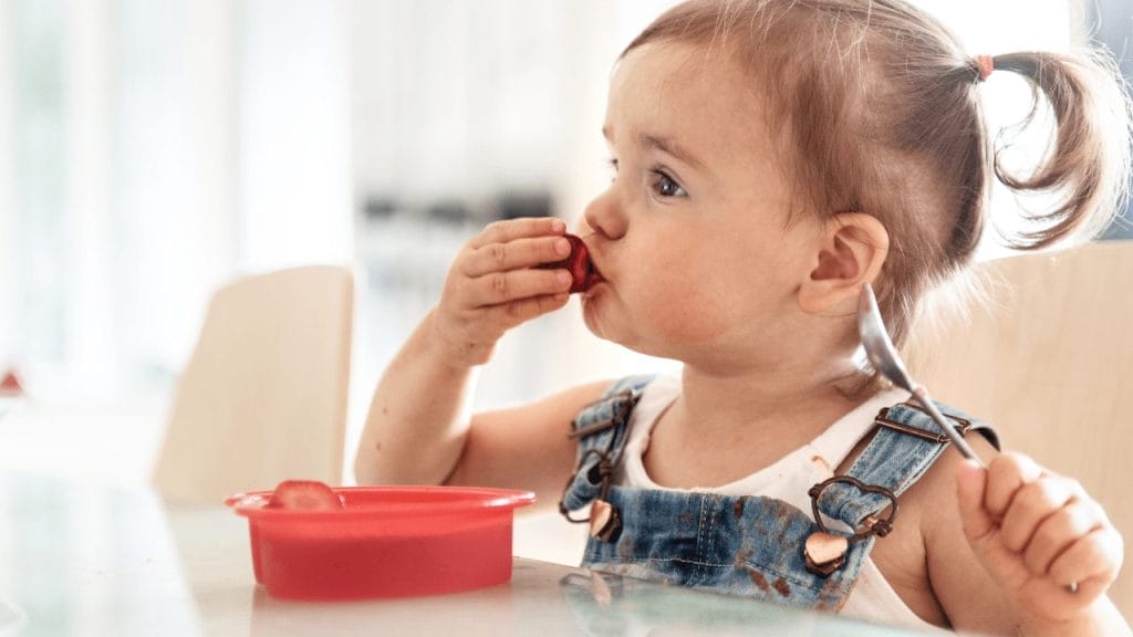 2 year old girl faces choking risk as she eats a big piece of strawberry